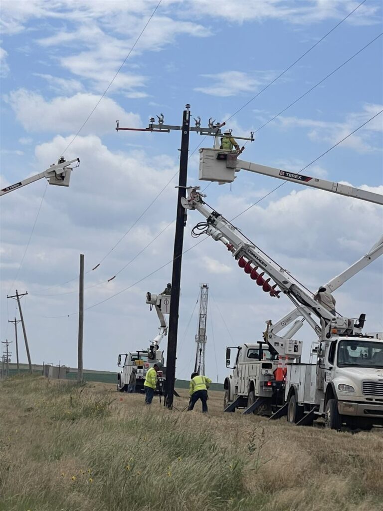 Crew installing a new utility pole in an open field
