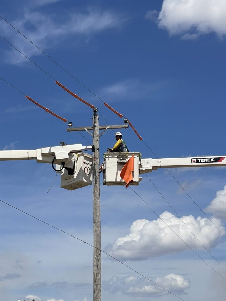 Lineman in a bucket truck installing a crossarm