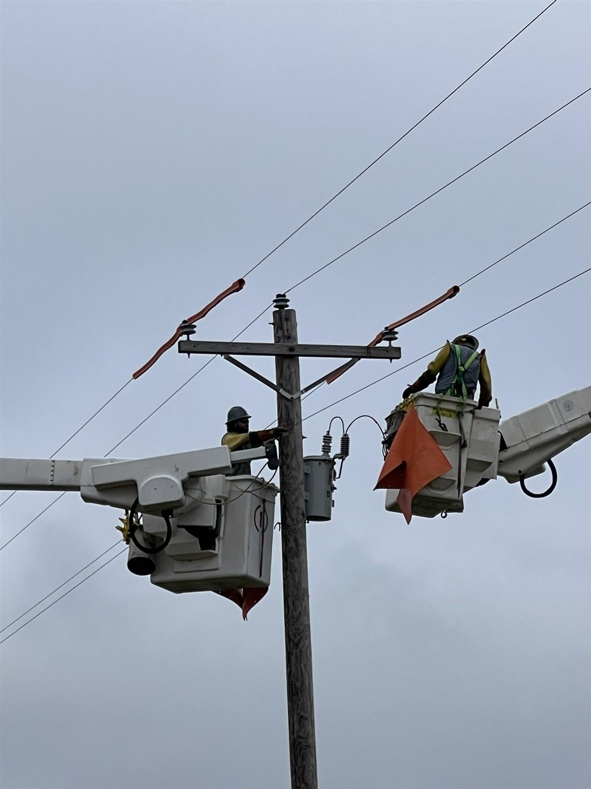 Linemen framing a crossarm on a distribution pole
